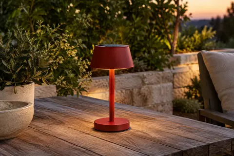 Lampe de table solaire rouge Eglo Simeri posée sur une table de terrasse au crépuscule.