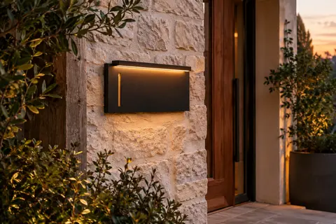 Plaque solaire noire en aluminium installée près d’une entrée, éclairée doucement au crépuscule