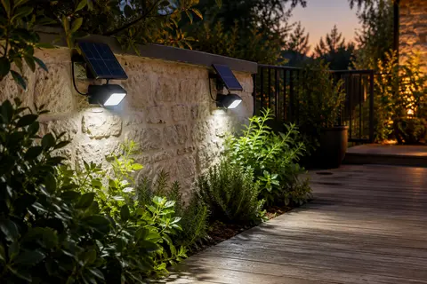Deux projecteurs solaires Lotmos avec panneaux déportés éclairent un passage de jardin au crépuscule.