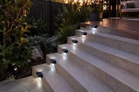 Huit lampes solaires noires à double diffusion installées sur des marches de jardin au crépuscule.